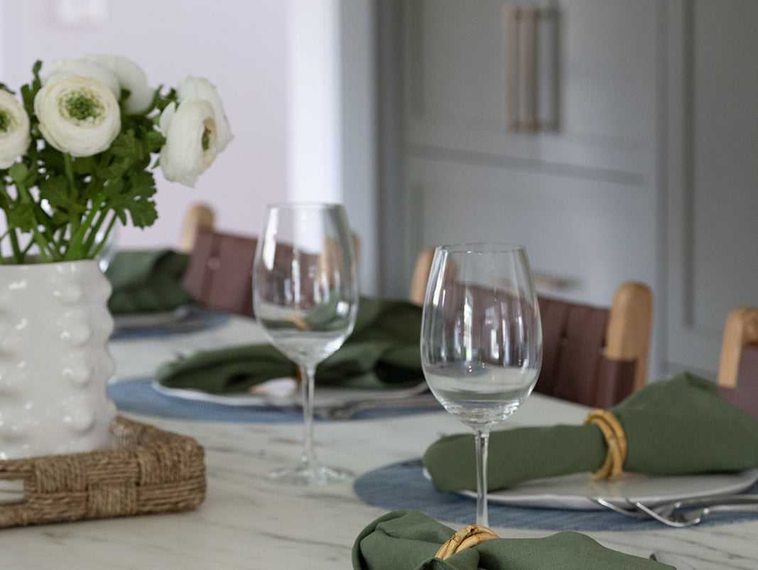 Kitchen island set for dining with green kitchen cabinets in background