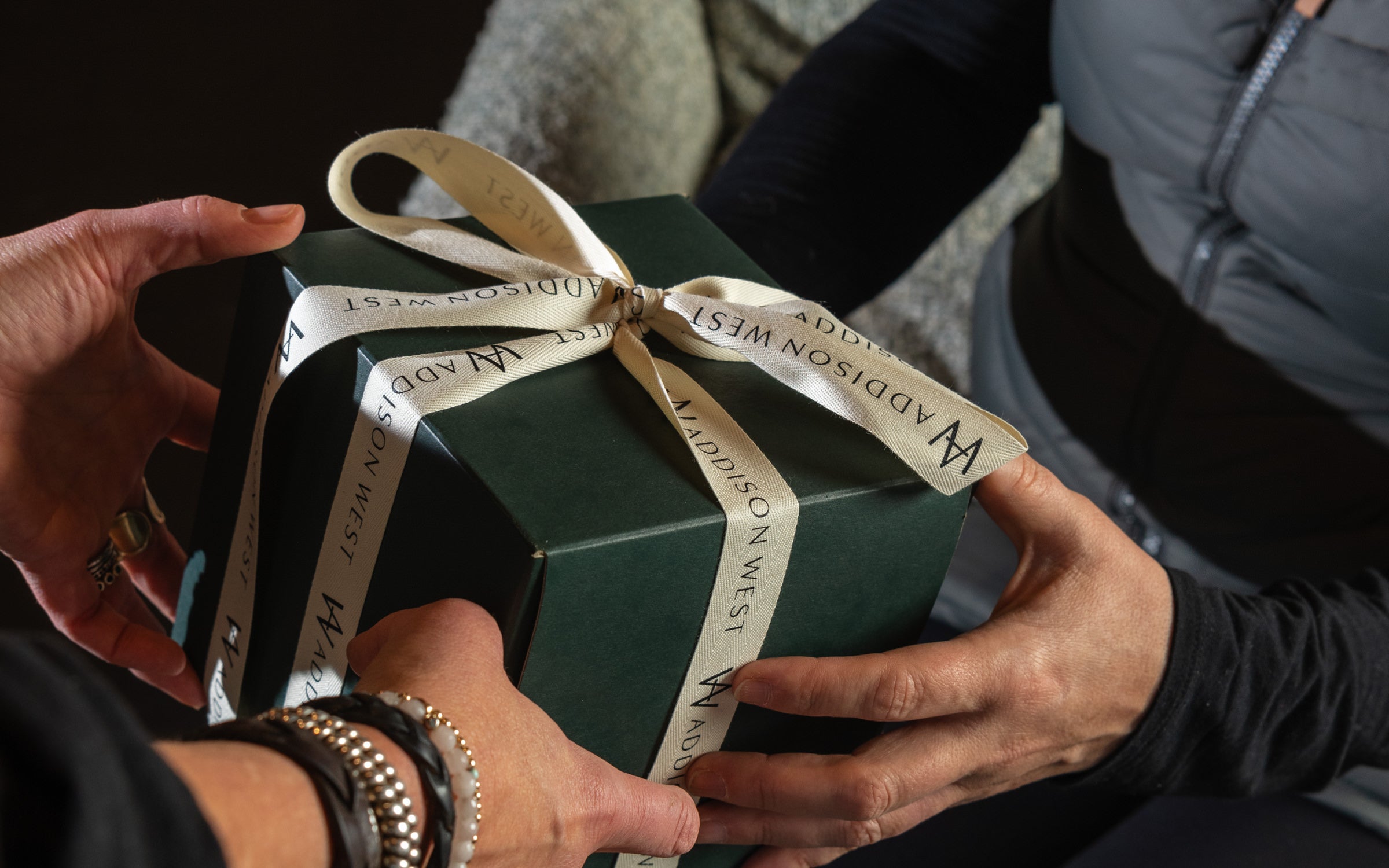 Person handing another person a gift wrapped in Addison West gift wrap at the Addison West gift guide
