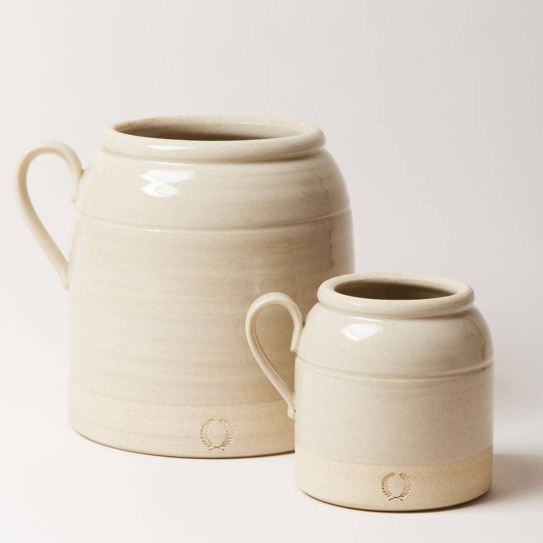 Two ceramic jars, one larger and one smaller, on a light background