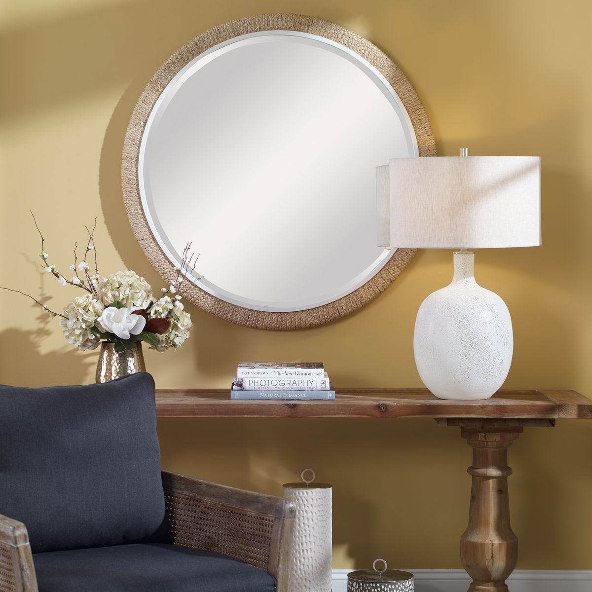 Carsten Round Accent Mirror on a yellow wall above a table at Addison West