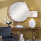 Carsten Round Accent Mirror on a yellow wall above a table at Addison West