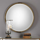 Finlow Round Accent Mirror on a grey wall above a table at Addison West