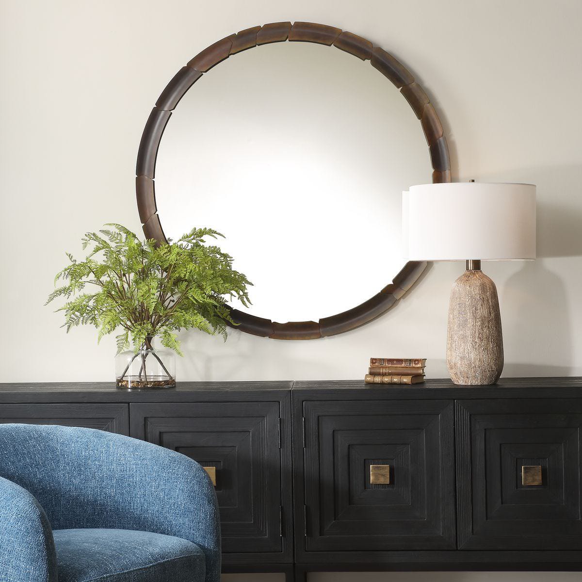 Augusta Round Accent Mirror on a beige wall above a table at Addison West