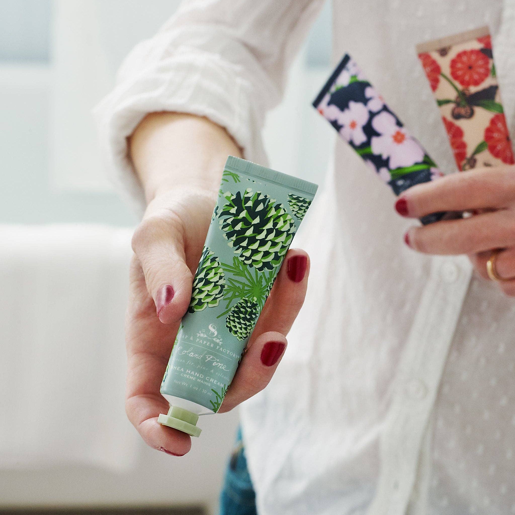 Model holding Roland Pine Shea Butter Hand Cream against a white background at Addison West