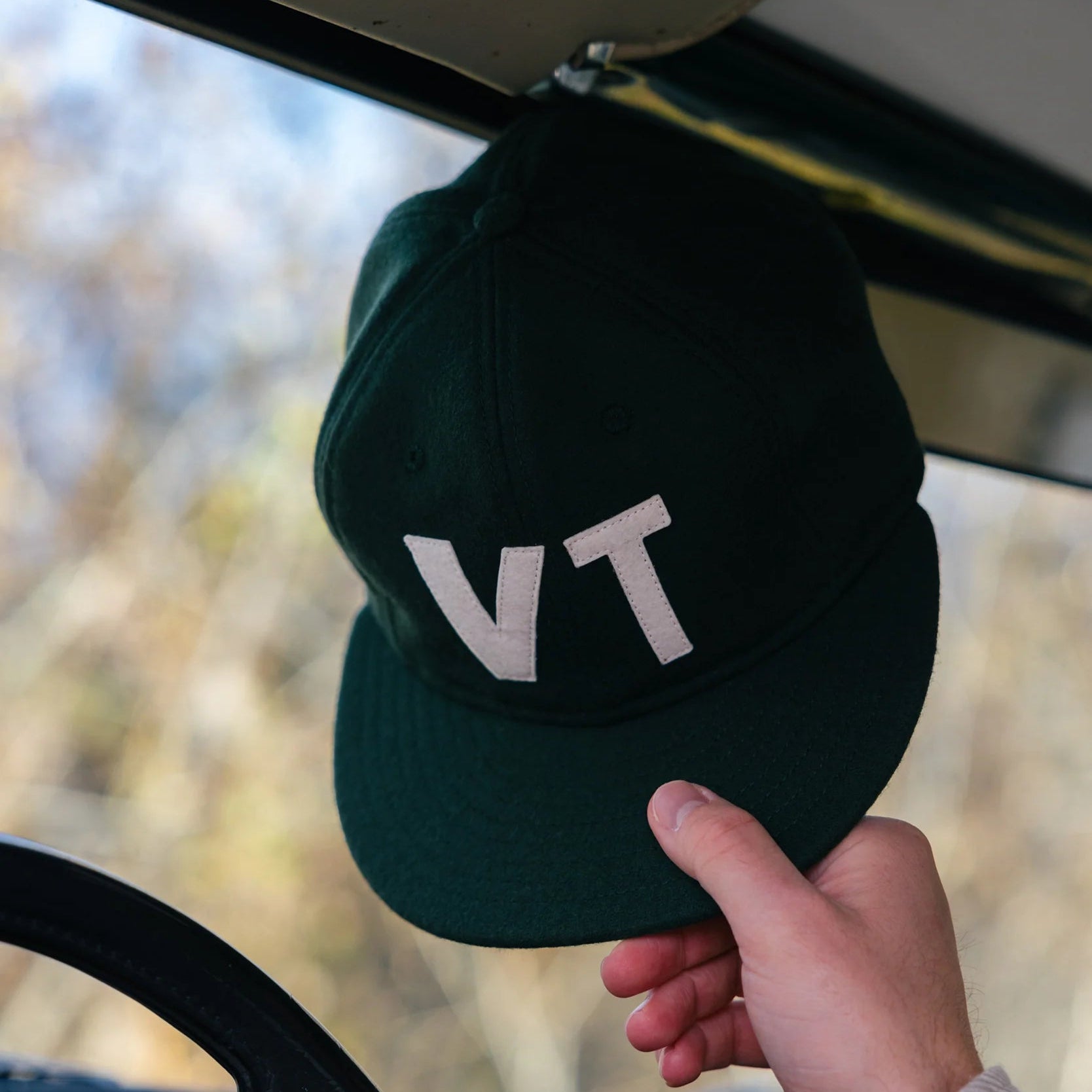 Warren Farm League Ballcap in Green Mountain State in a car at Addison West