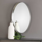 Purwell Oval Accent Mirror on a beige wall above a table at Addison Wet