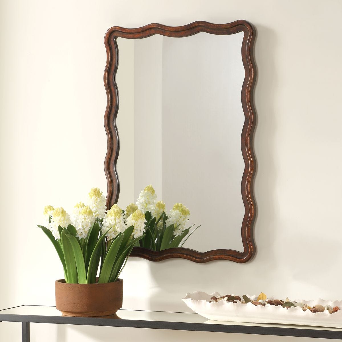 Mirelle Accent Mirror on a white wall above a table at Addison West