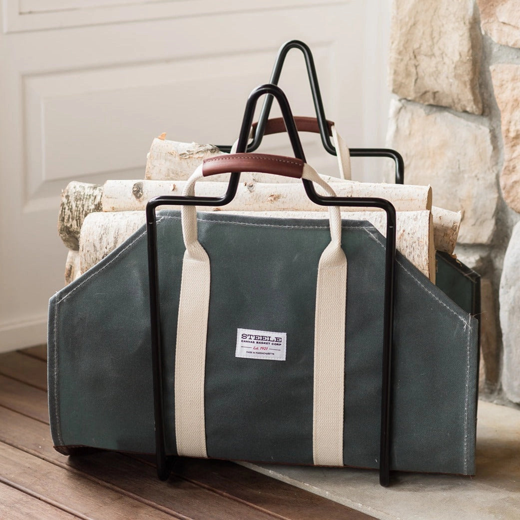 Steele Canvas and Leather Wood Carrier in Forest Green next to a fireplace at Addison West