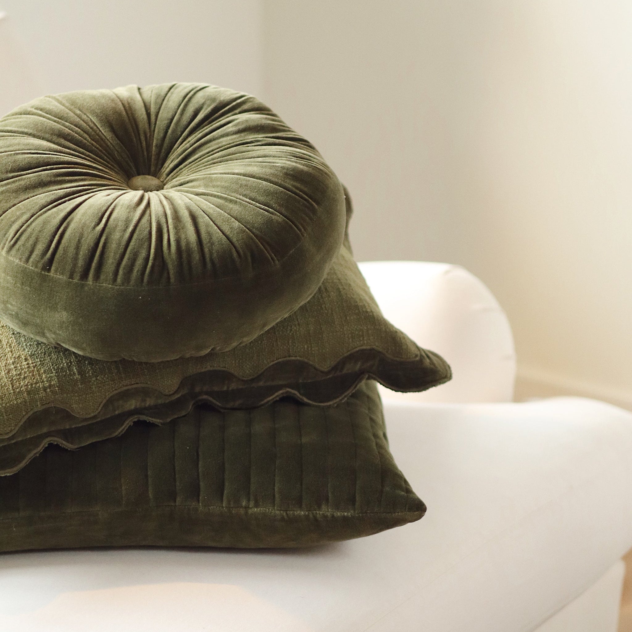 Velvet Tuft Round Cushion in Moss on a white sofa at Addison West