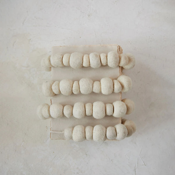 Cream felted wool ball garland on a white background