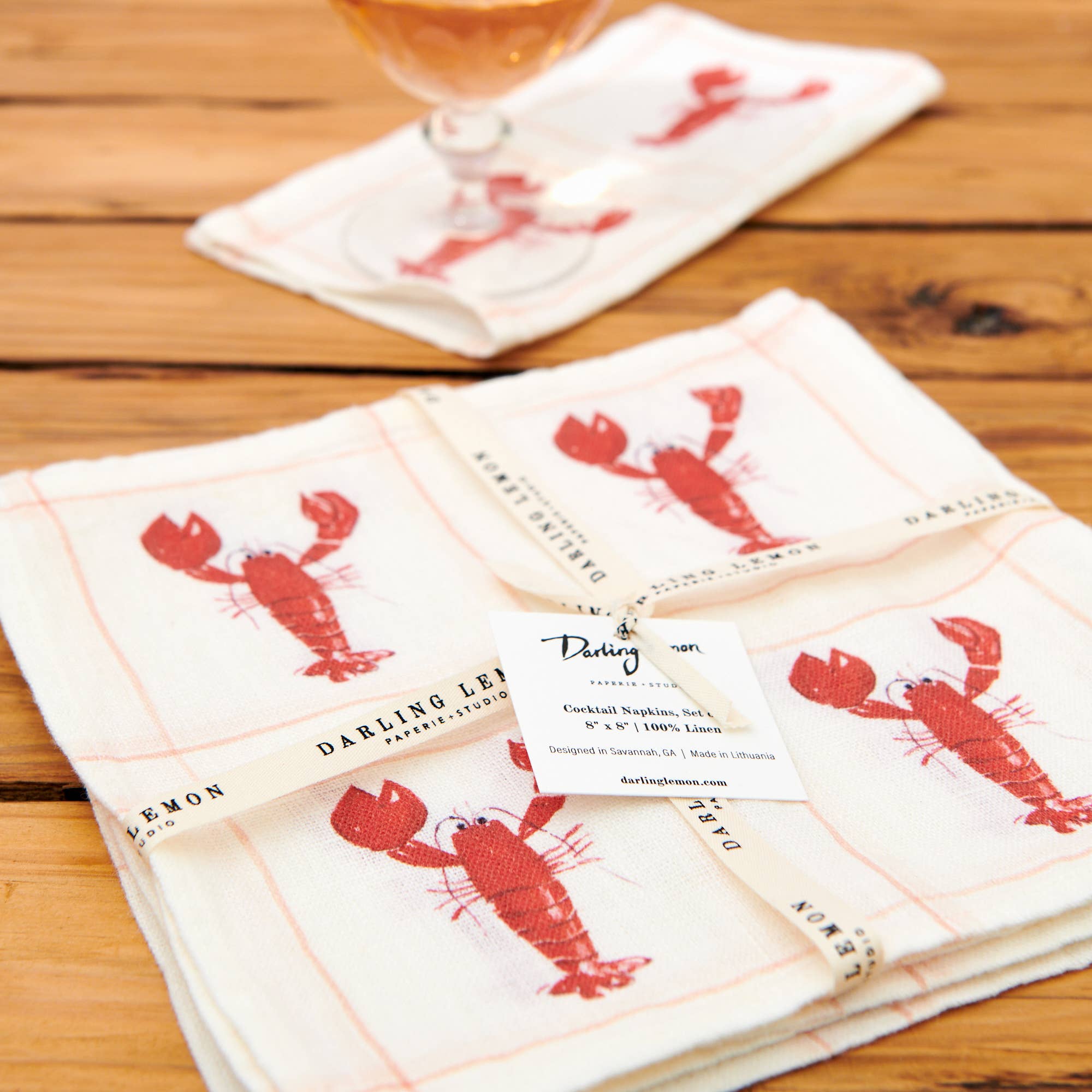 Set of cocktail napkins with red lobster design on a wooden surface