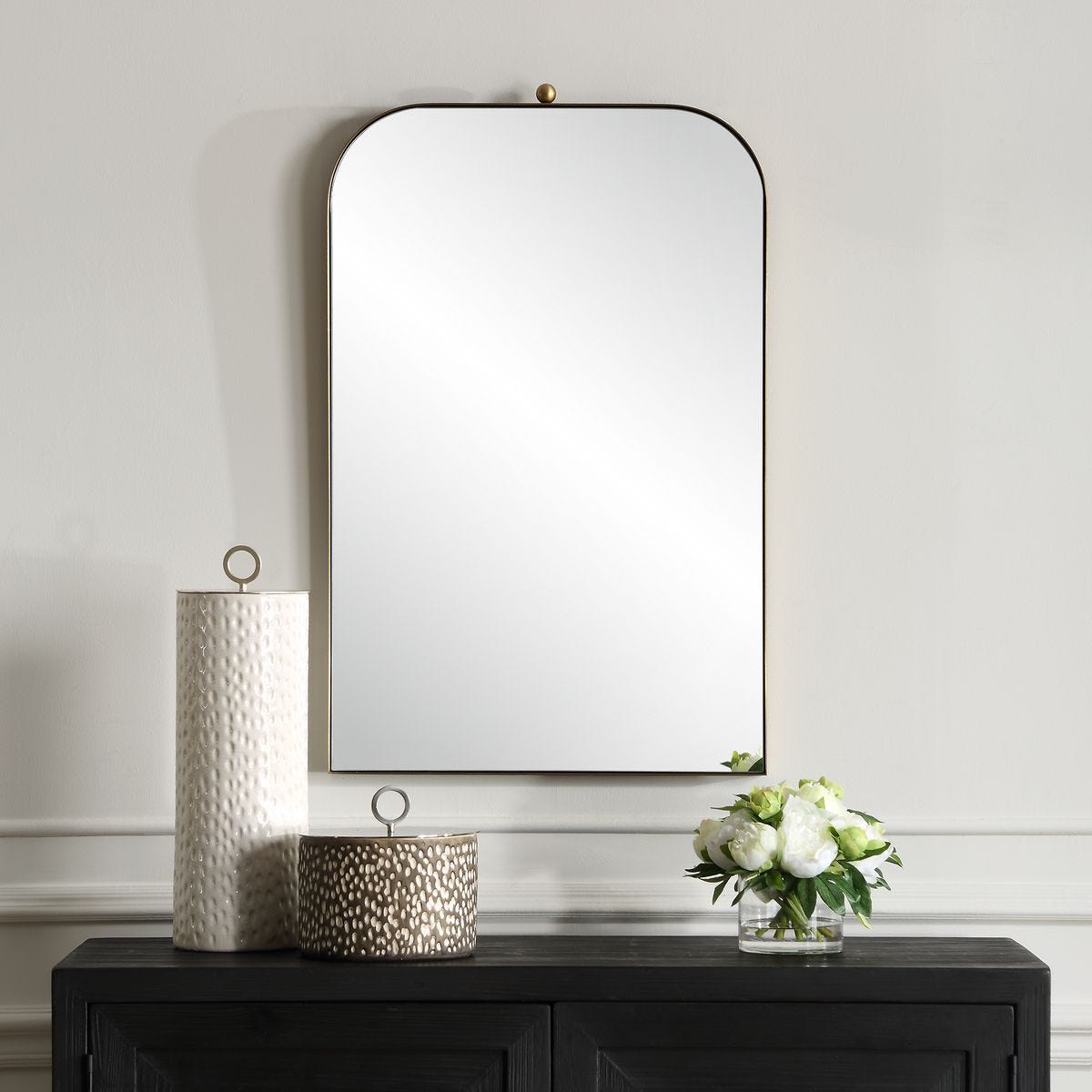Caswell Arch Accent Mirror on a white wall above a table at Addison West