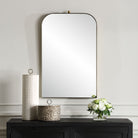 Caswell Arch Accent Mirror on a white wall above a table at Addison West