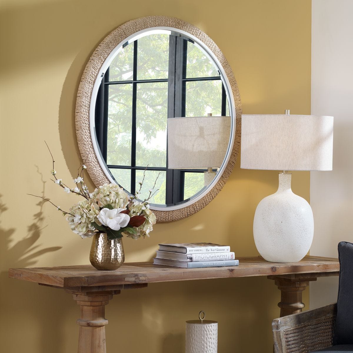 Carsten Round Accent Mirror on a yellow wall above a table at Addison West