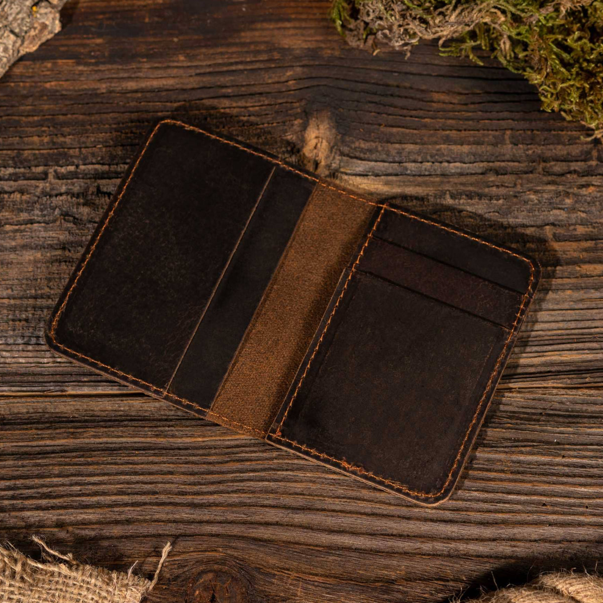 Leather Vertical Bifold Wallet in Dark Brown on a table at Addison West