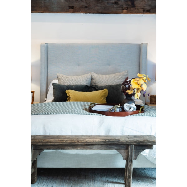 Queen size bed with headboard and pillows layers including mustard yellow velvet pillow with scallopped edge