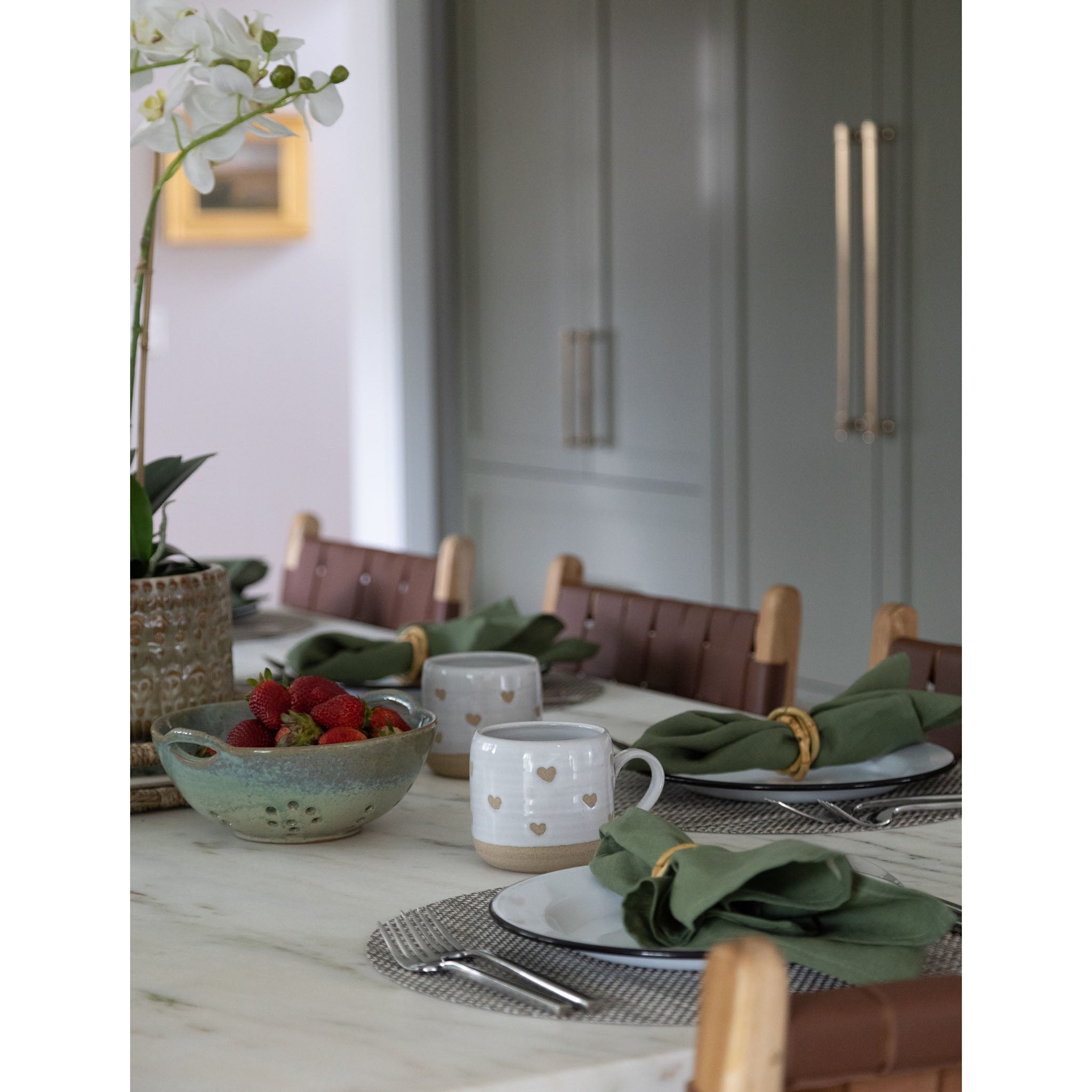 Blue Green glazed berry bowl on a kitchen counter with place settings and mugs