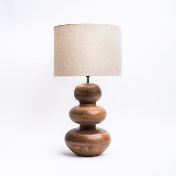 Mango wood table lamp with curved base and linen shade on white background 