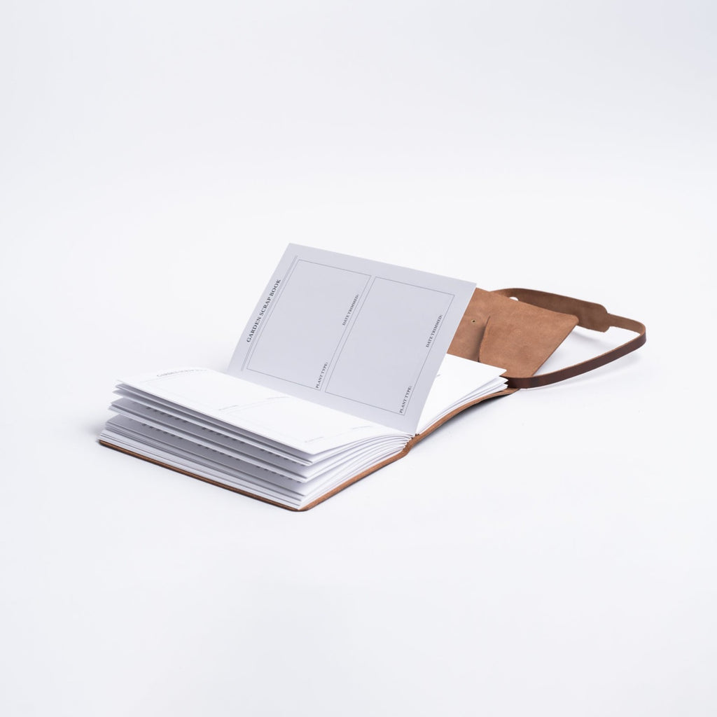 Handmade leather garden journal from above with lined log pages on white background