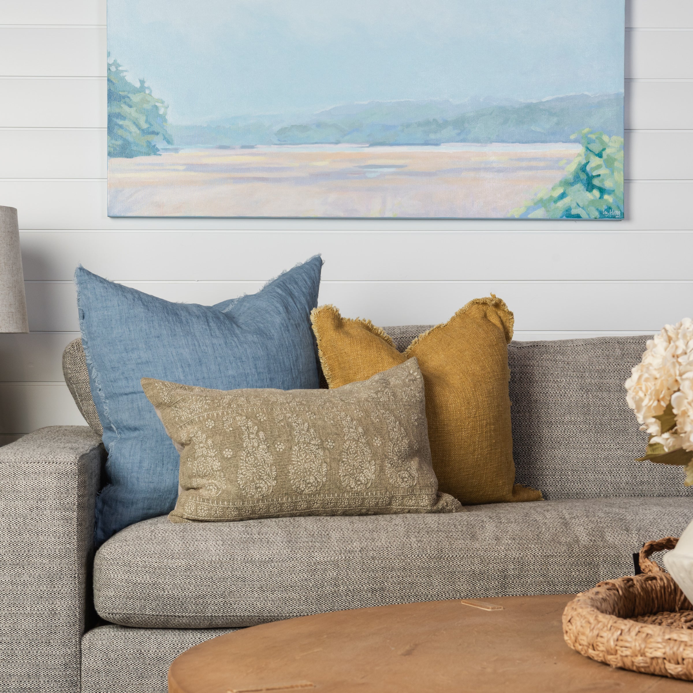 Lina Linen 24" Square Pillow in Arctic Blue, Selena Linen 20" Square Pillow in Desert Yellow, and Nisha Lumbar Pillow in Sage on a beige sofa at Addison West