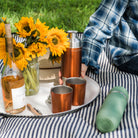 High Camp Firelight Flask in Copper on a picnic blanket with a model at Addison West