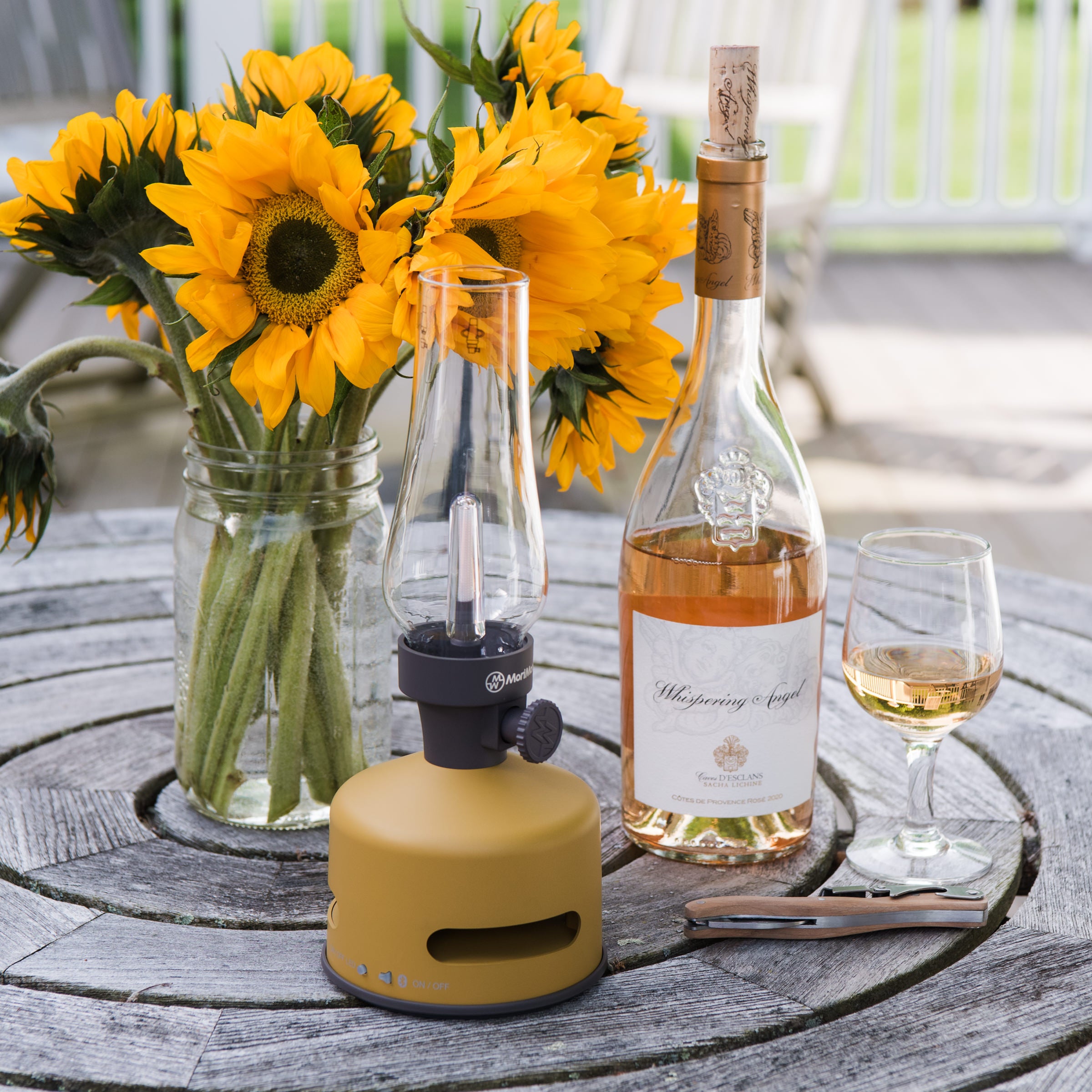 Light and Sound LED Lantern with Speaker in Mustard Yellow on a table outside at Addison West