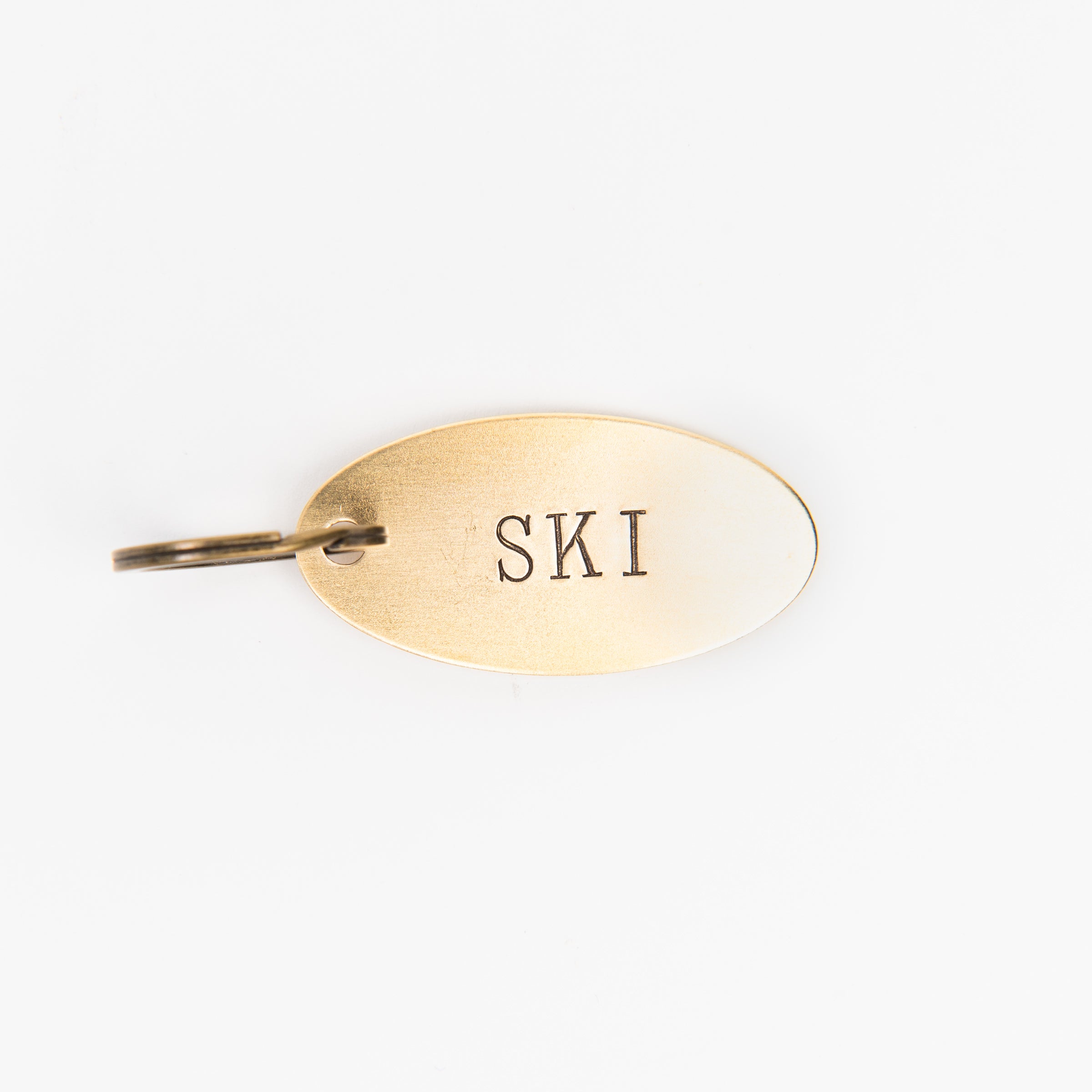 SKI Oval Brass Key Ring on a white background at Addison West
