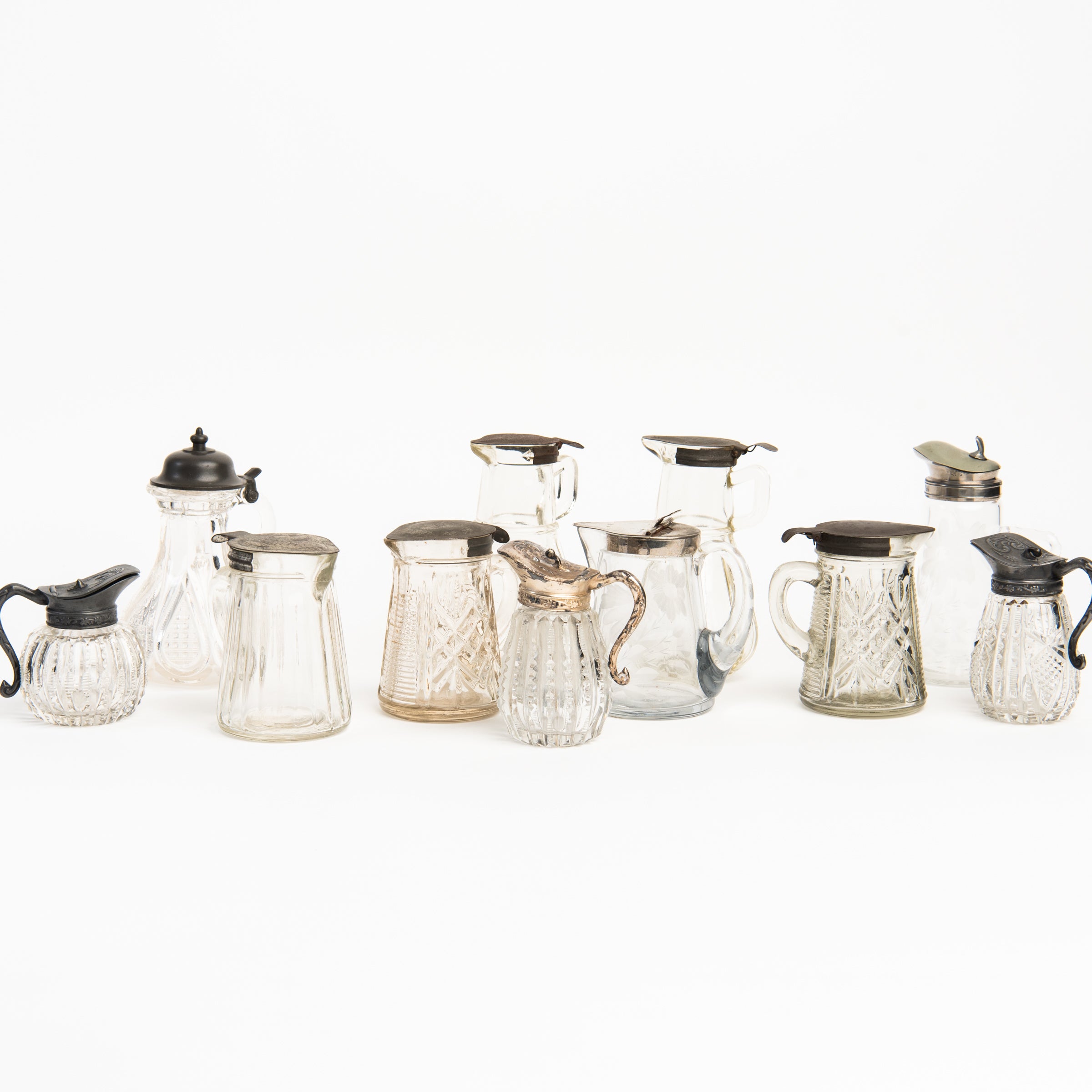 Collection of vintage syrup and molasses cruets and pitchers on a white background at Addison West