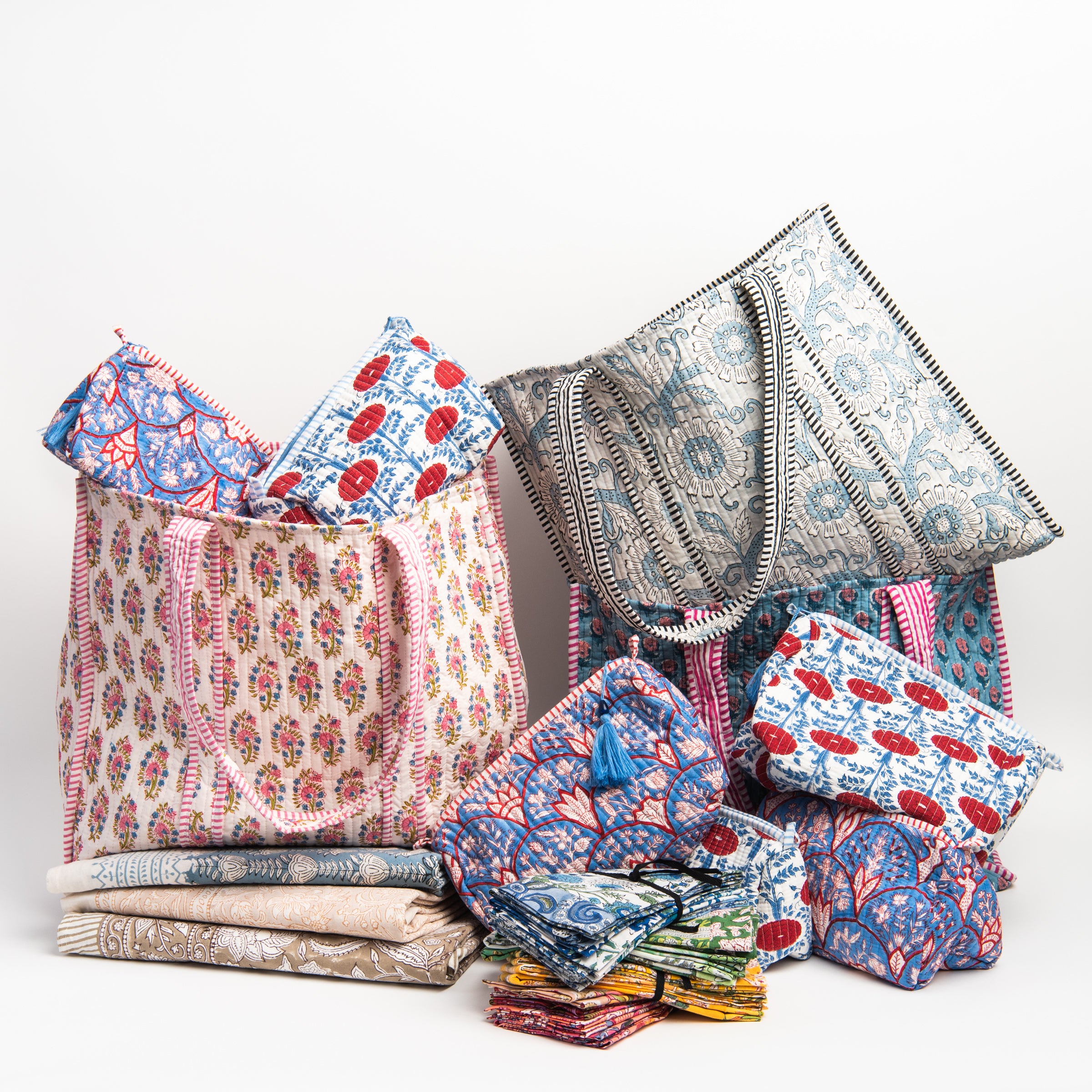 Collection of block printed bags, cosmetic bags, napkins, and table cloths on a white background at Addison West