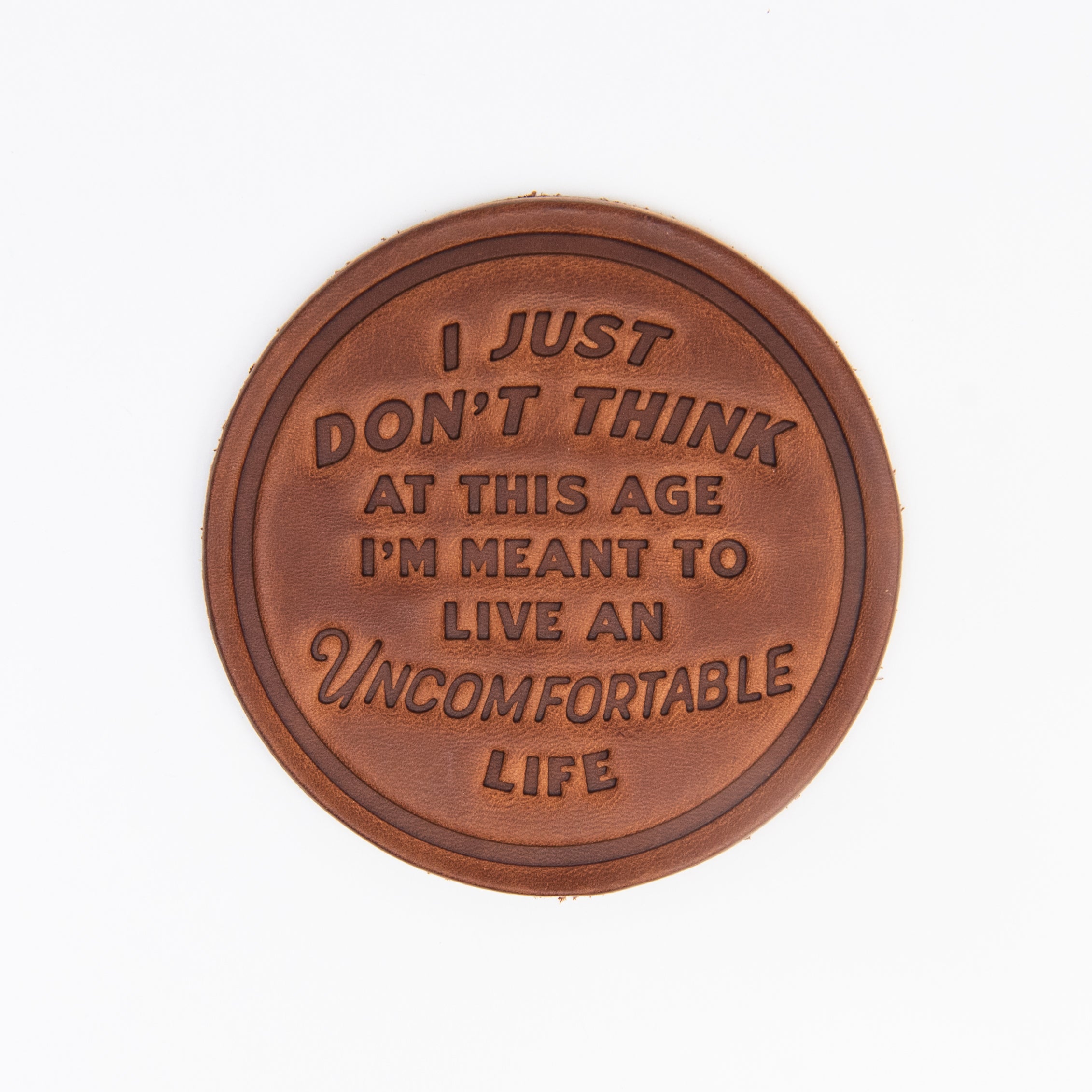 'An Uncomfortable Life' Leather Coaster on a white background at Addison West
