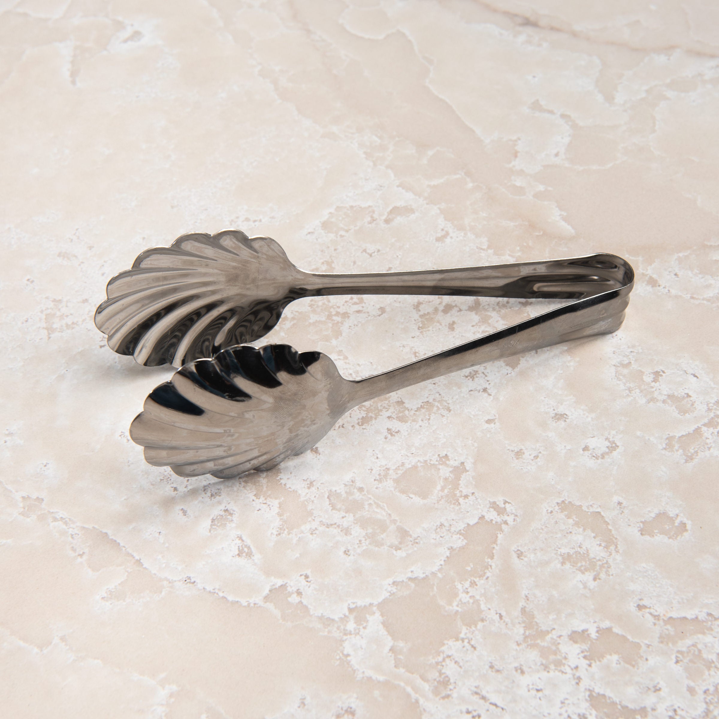 Scalloped Serving Tongs on a beige background at Addison West
