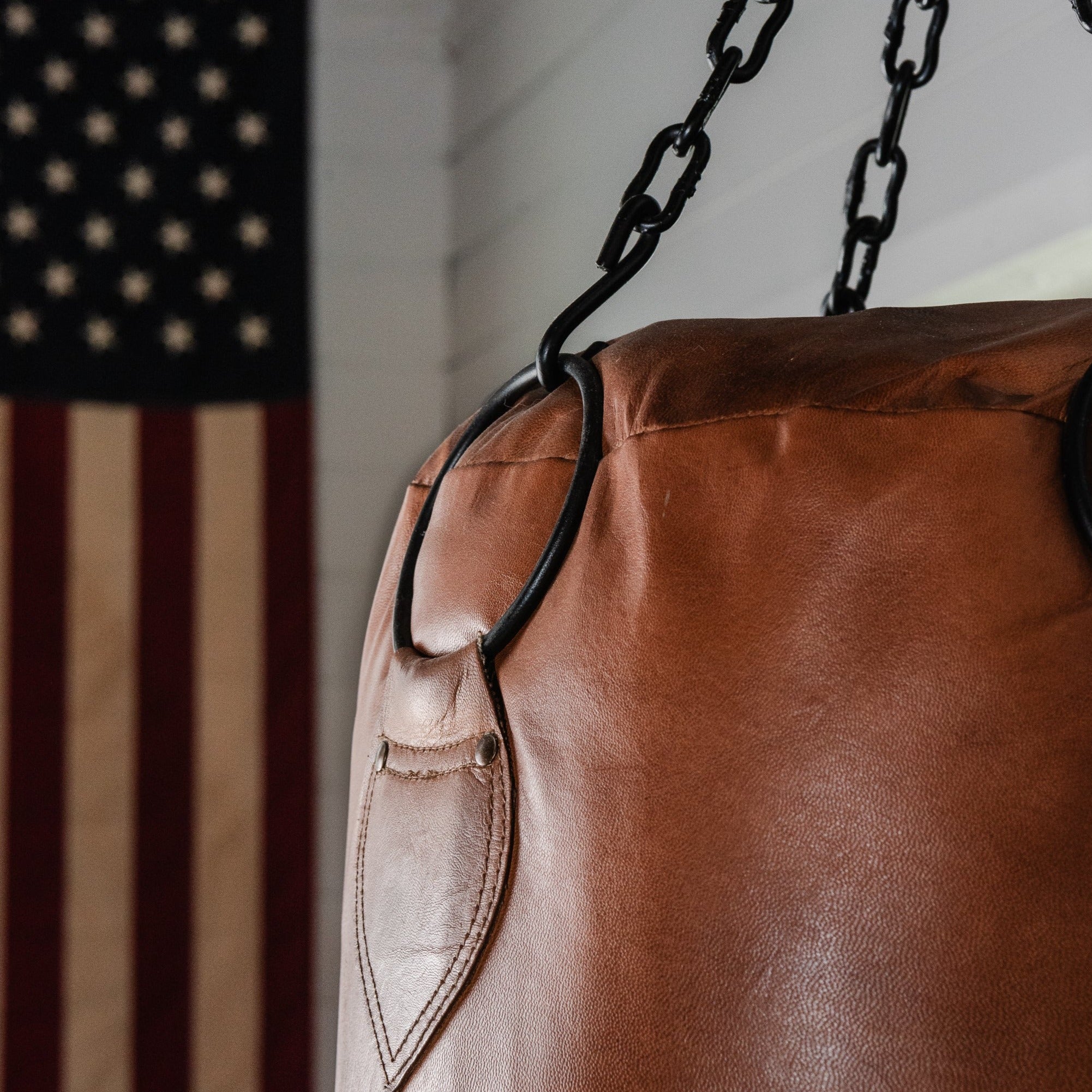 Pugilist Bag vintage punching bag in a room with ship lap walls and and American flag in the background