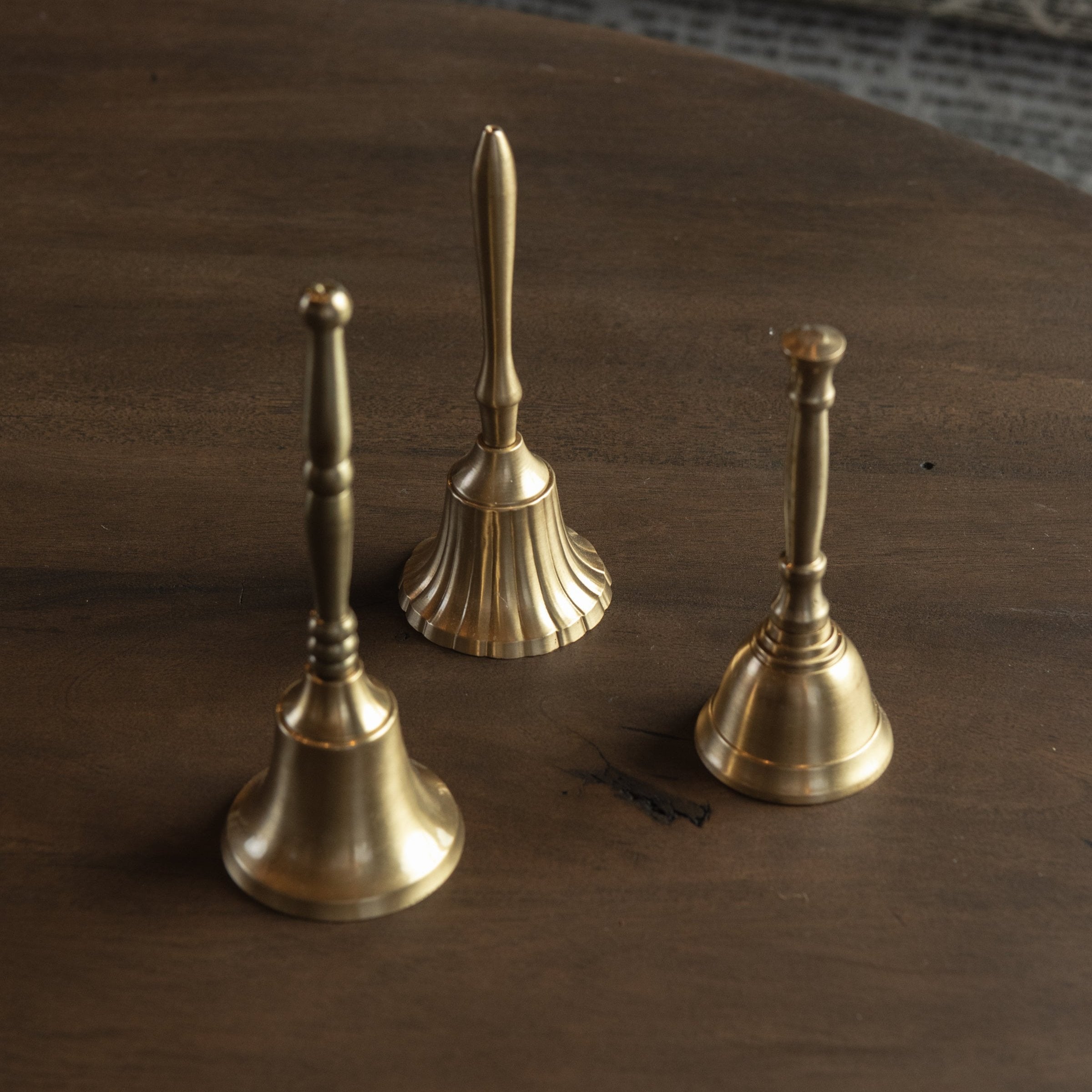 Three Decorative Bells on a dark wood table at Addison West