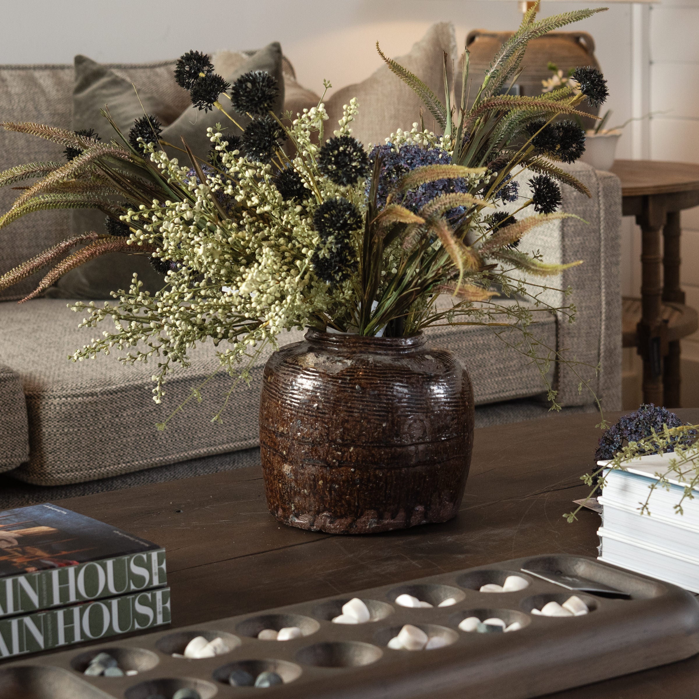 Vintage Bean Pot with faux flowers on a wood coffee table at Addison West