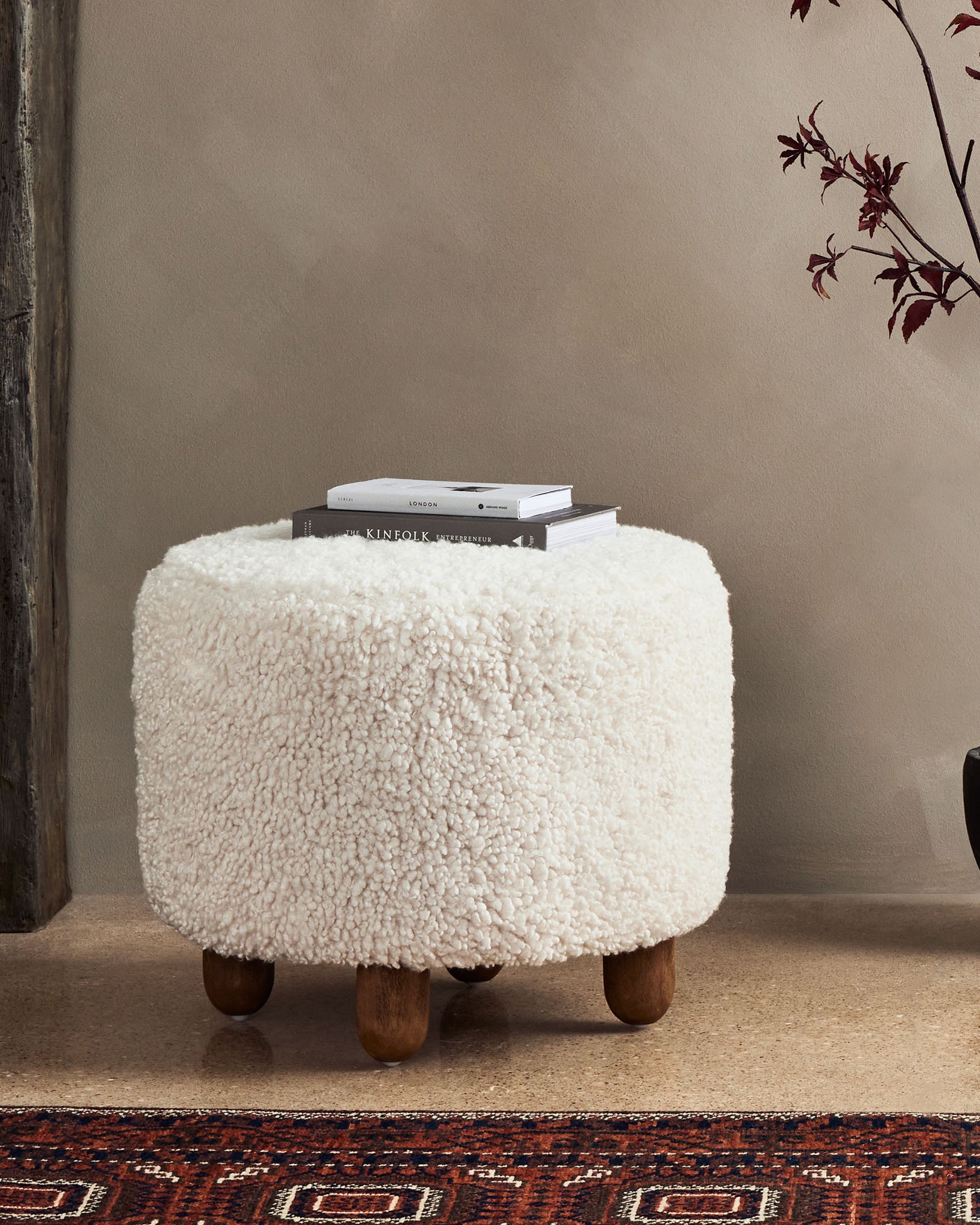 Four hands brand Aniston ottoman in natural shearling style upholstery in a room with an antique rug