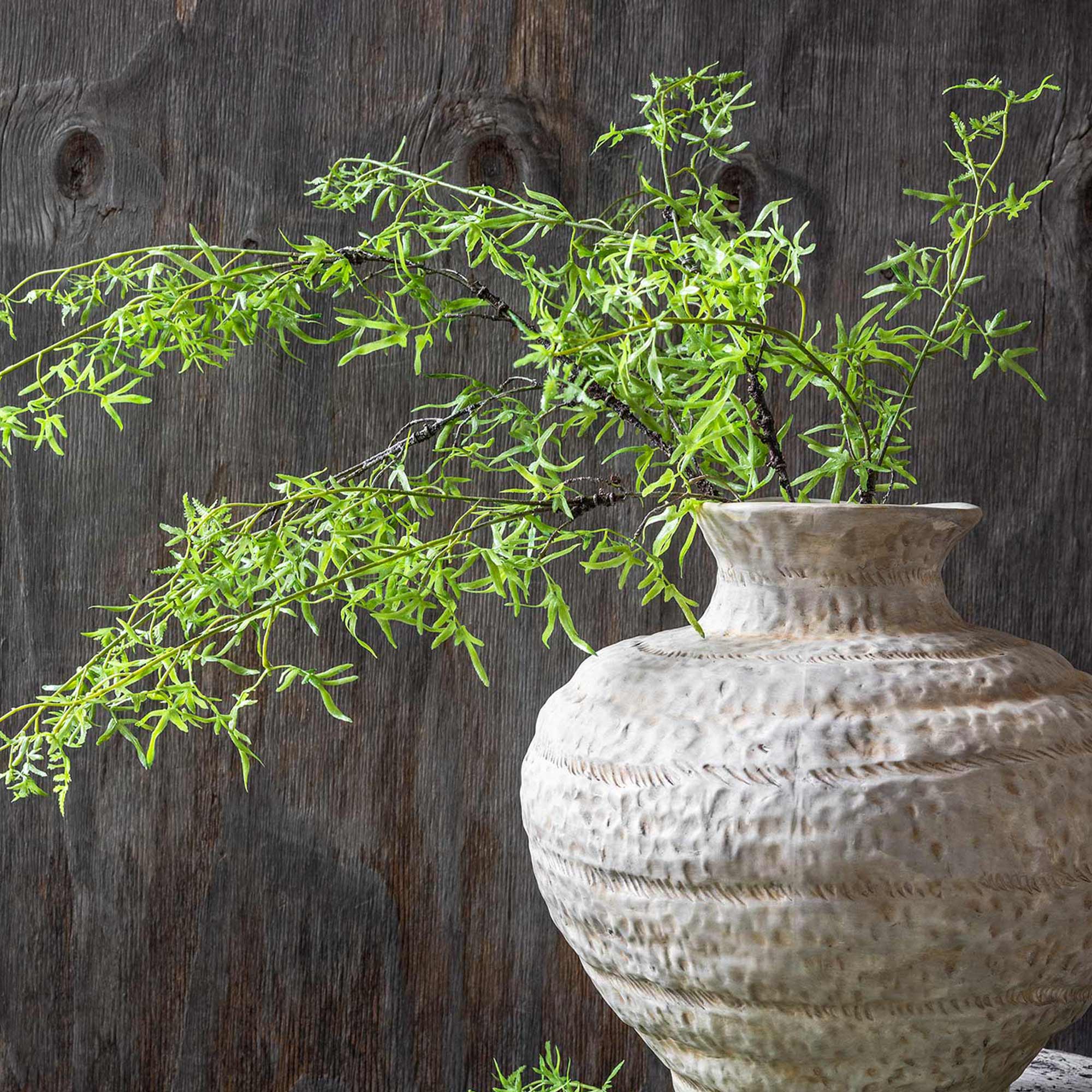 Abigail Ahern Faux Fern Branch in Soft Green in a vase on a grey background at Addison West