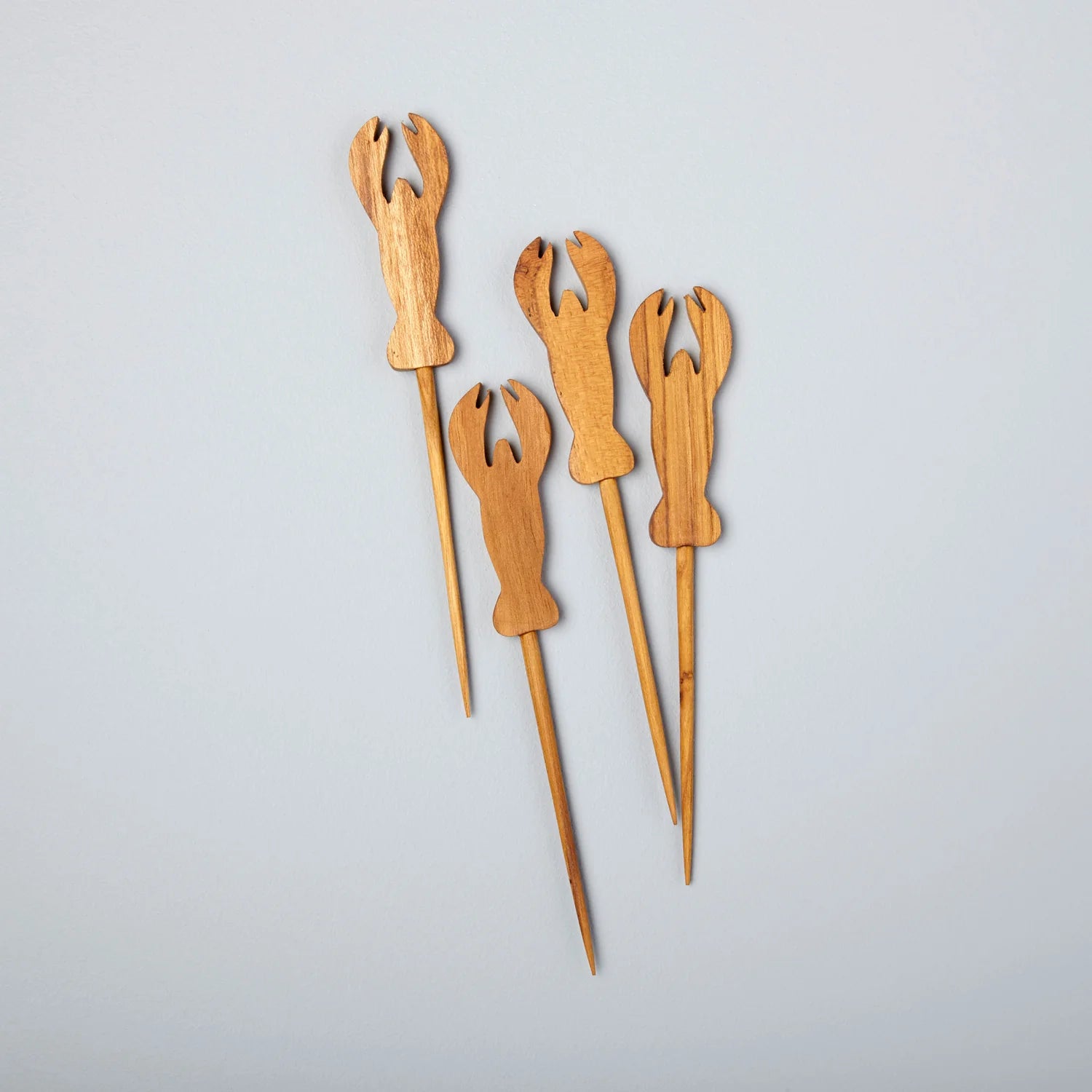 Set of four wooden lobster skewers on a light gray background