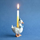 Decorative duck candle holder with a lit candle on a blue background