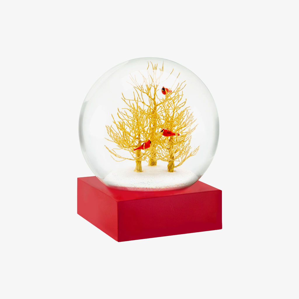 Snow globe with golden trees and three red cardinals on a red base and white background