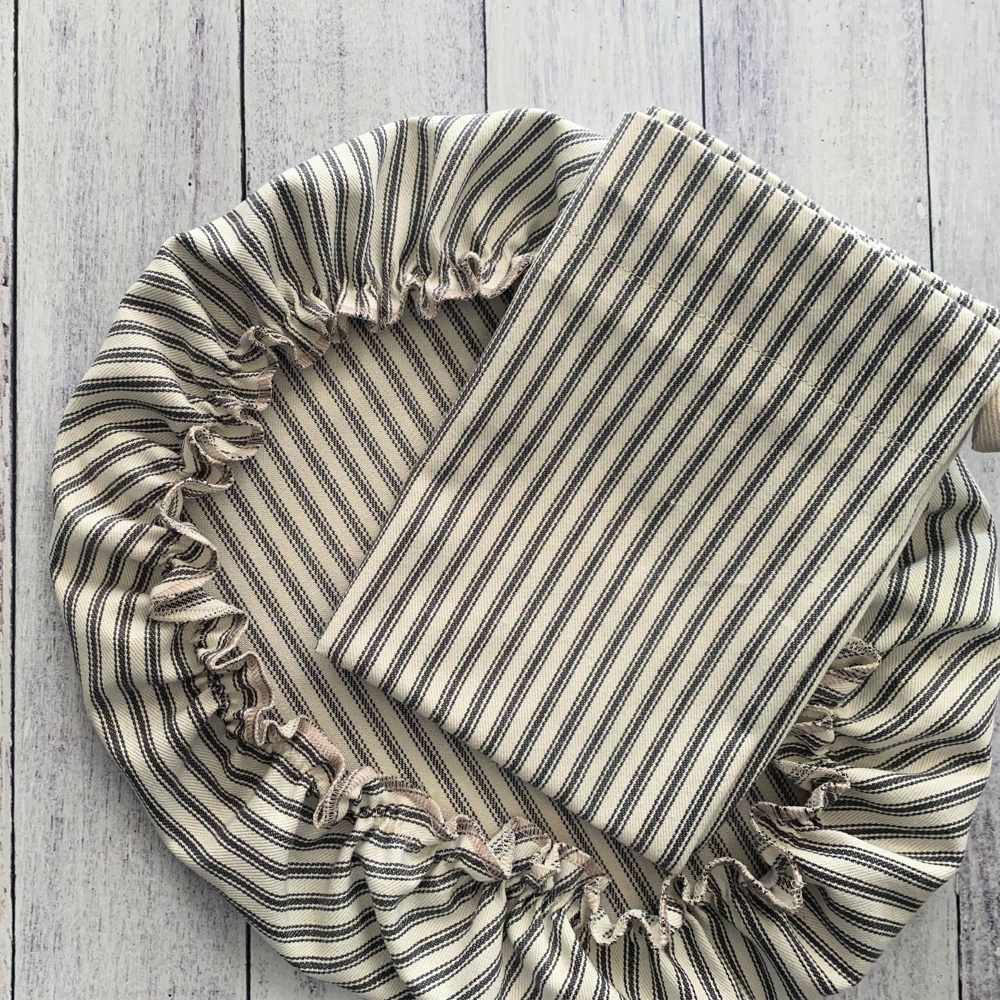 Set of two bag and bowl cover for bread making in Striped fabric with ruffled edges on a wooden surface