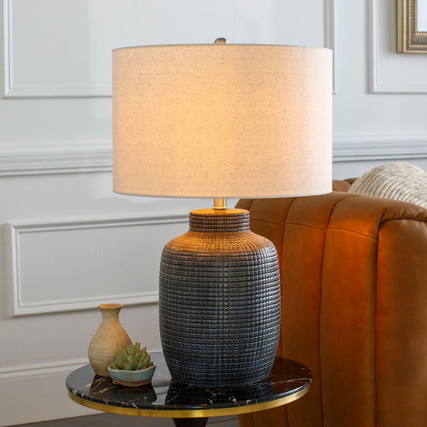 Surya brand black textured Brie lamp on a small side table in a living space with white walls