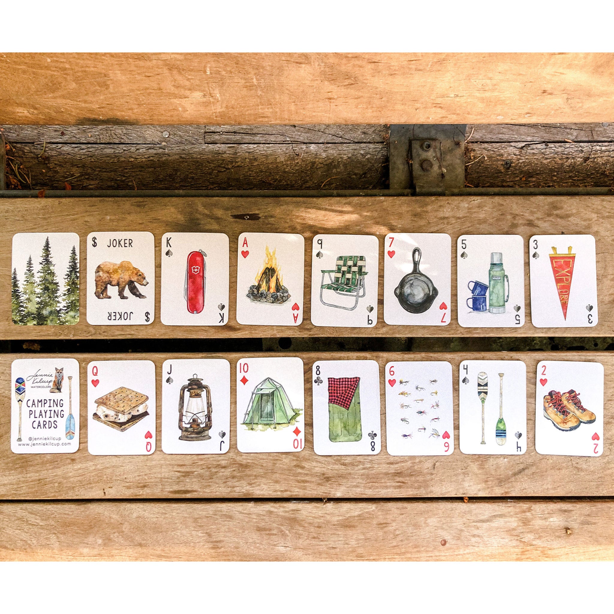 Various playing cards with camping images on themm on a wooden table.