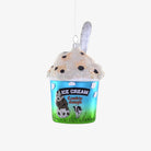 A painted glass ornament shaped like a pint of cookie dough ice cream with a blue base color and white ice cream topping, decorated with chocolate chip details.