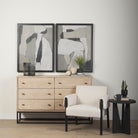 White washed wood six drawer dresser with metal base in a living space with a white chair and black side table