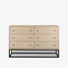 White washed wood six drawer dresser with metal base on a white background