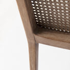 Close up of Clara Light Brown Wood W/ Cream Fabric Seat and Cane Back Armless Dining Chair on a white background
