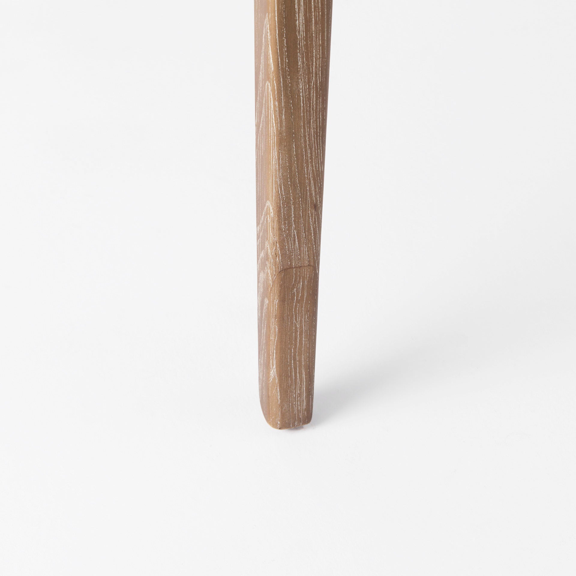 Close up of leg of Clara Light Brown Wood W/ Cream Fabric Seat and Cane Back Armless Dining Chair on a white background