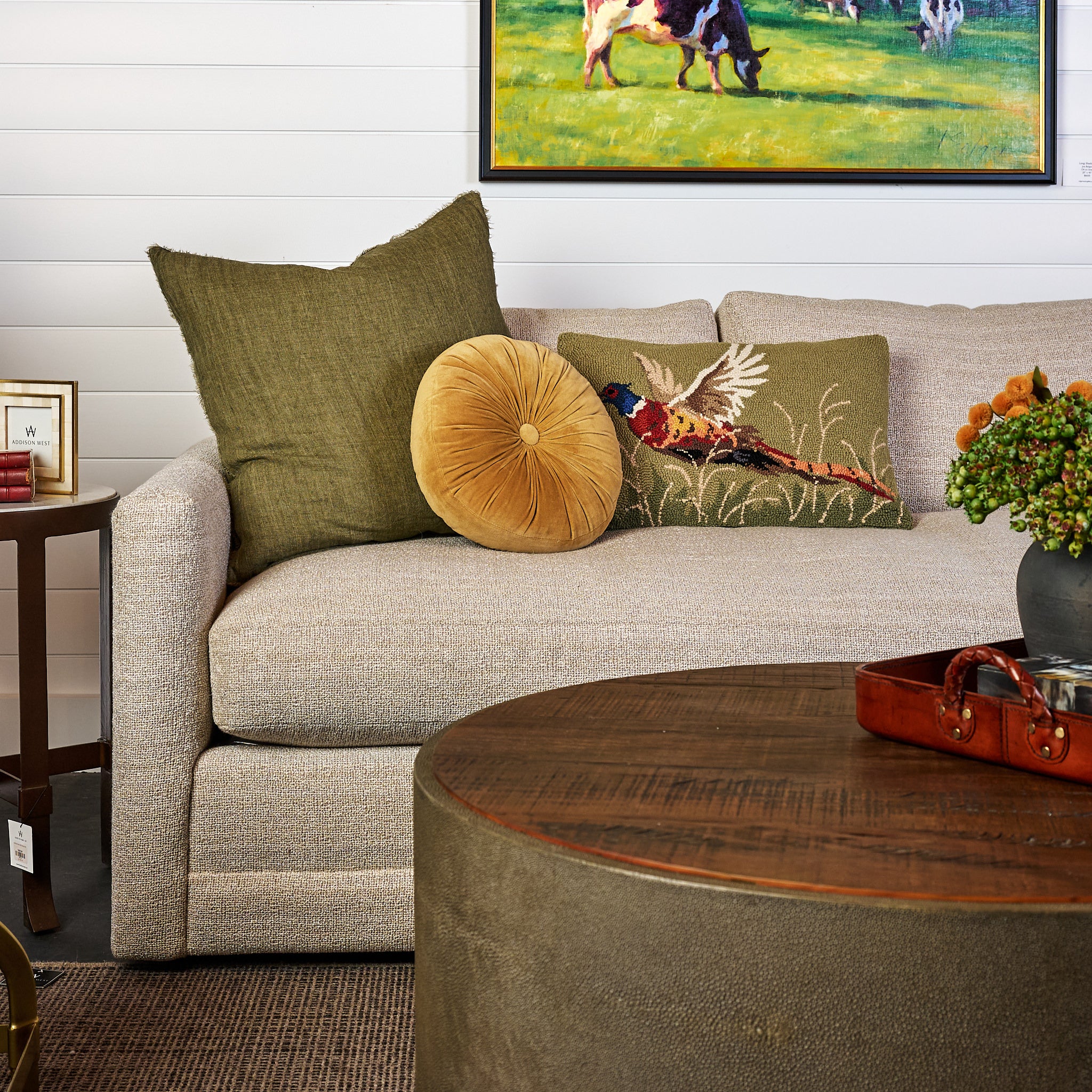 Velvet Tuft Round Cushion in Gold and Lina Linen 24" Square Pillow in Kelp and Pheasant Hand Hooked Pillow on a sofa at Addison West