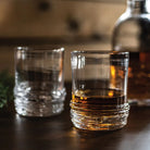 Simon Pearce Echo Lake Whiskey Glass, Set of 2 on a wood table at Addison West