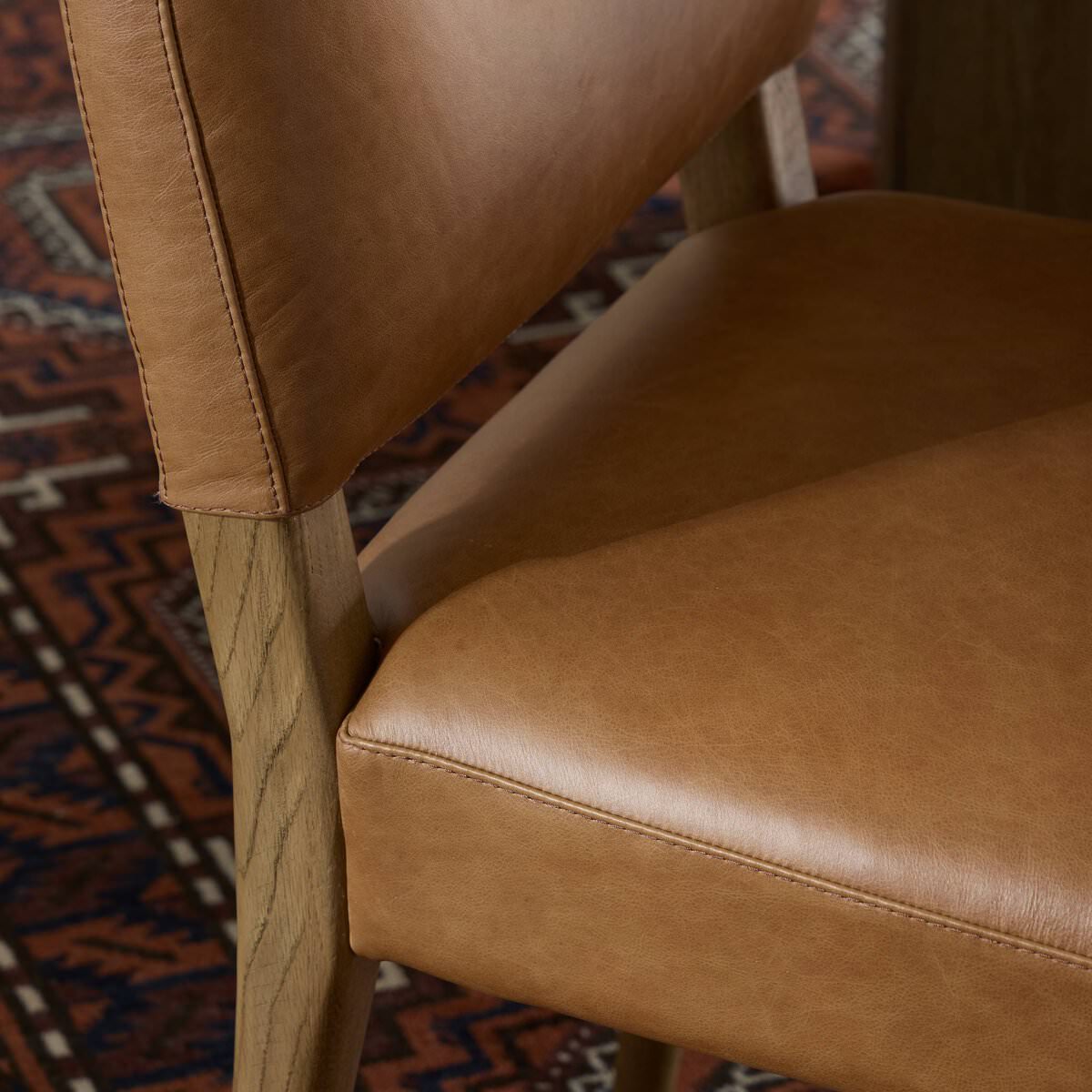 Close up of Four Hands Abilene Dining Chair in Chaps Saddle against a rug at Addison West